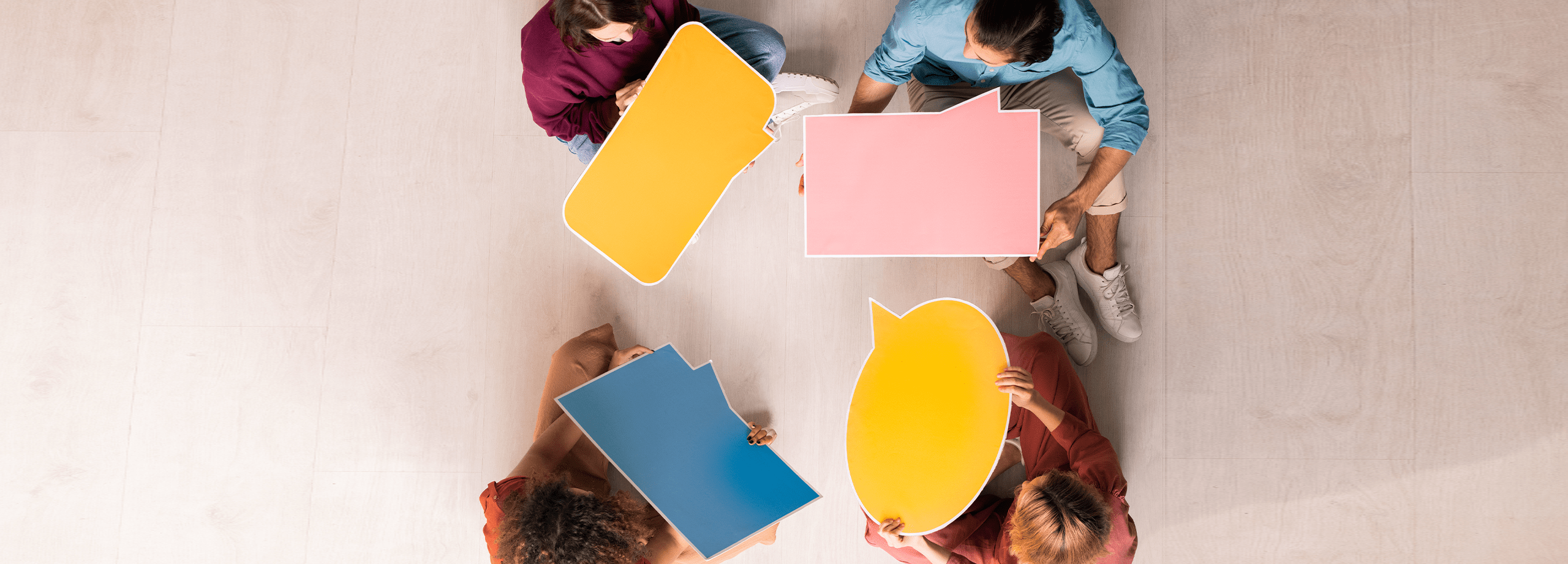 Photo of four people sitting in a circle with speech bubbles indicating asking questions