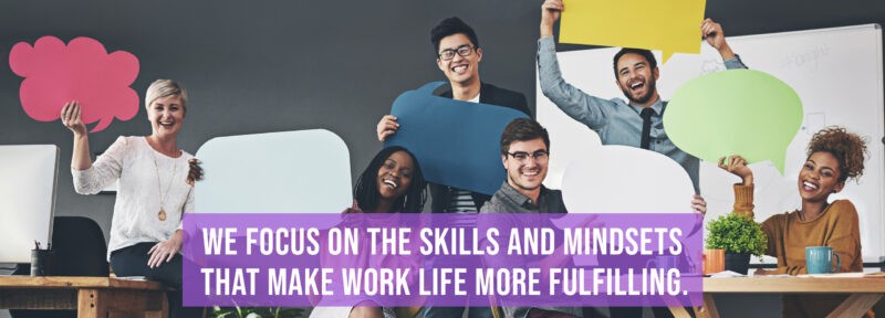 Photo of a group of professional adults holding speech bubbles with the tagline "We Focus On The Skills And Mindsets That Make Life More Fulfilling."